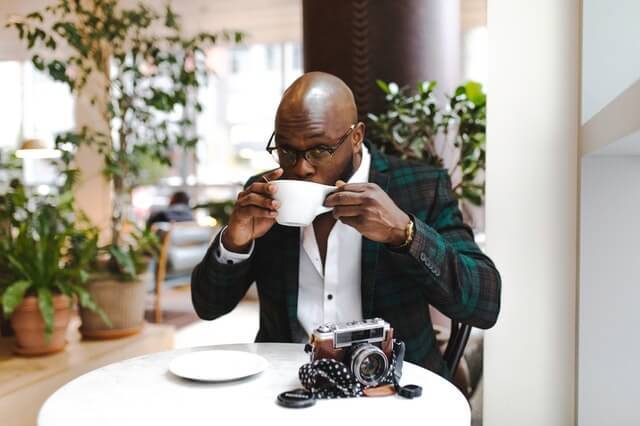 Elegant black man drinks coffe in the restaurant